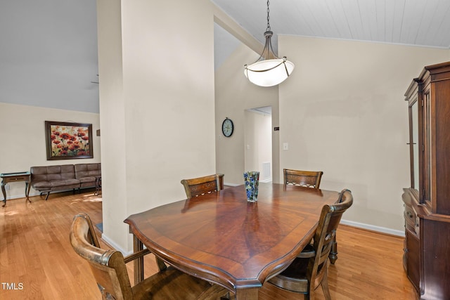 dining area with light wood-style flooring, lofted ceiling, and baseboards