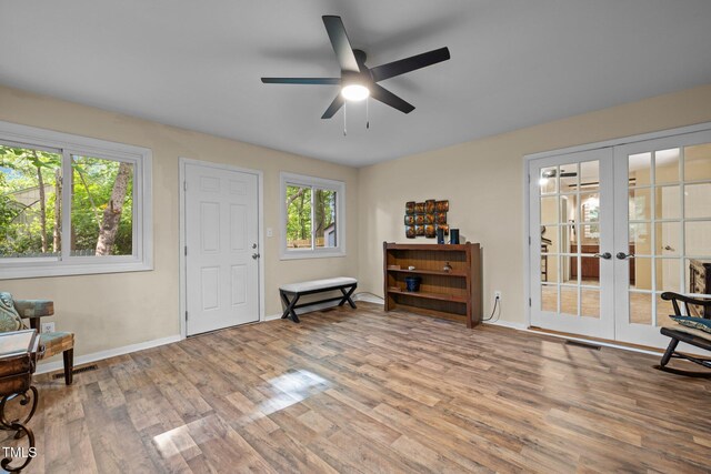 living area with french doors, wood finished floors, a ceiling fan, and baseboards