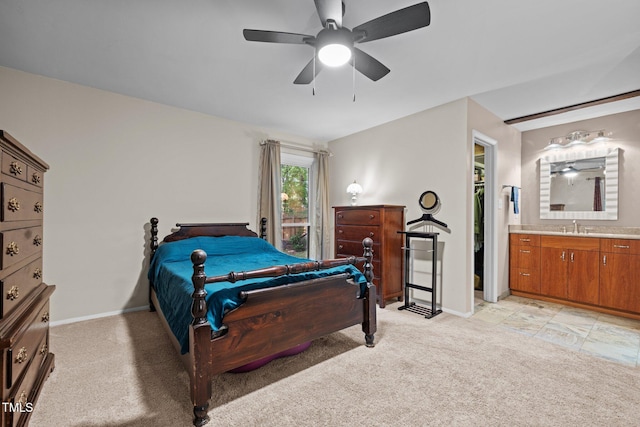 bedroom with light colored carpet, a sink, baseboards, ensuite bathroom, and a ceiling fan