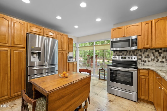 kitchen featuring stainless steel appliances, tasteful backsplash, recessed lighting, light stone counters, and brown cabinets