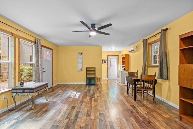 sitting room with a wall mounted air conditioner, hardwood / wood-style flooring, ceiling fan, and baseboards