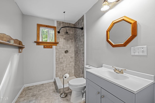full bath featuring tiled shower, vanity, toilet, and baseboards