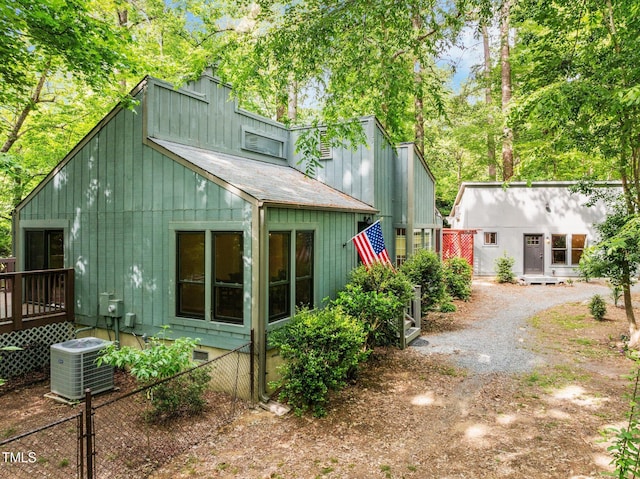 rear view of property featuring central AC, fence, a chimney, a wooden deck, and dirt driveway