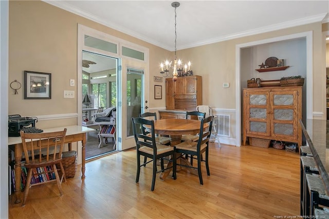 dining area with light wood-style floors, crown molding, and a chandelier