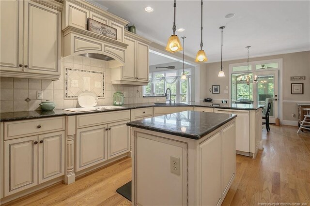 42 Skipping Water Dr, Spring Lake, NC 28390 - kitchen with cream cabinets, a peninsula, a sink, white electric stovetop, and a center island