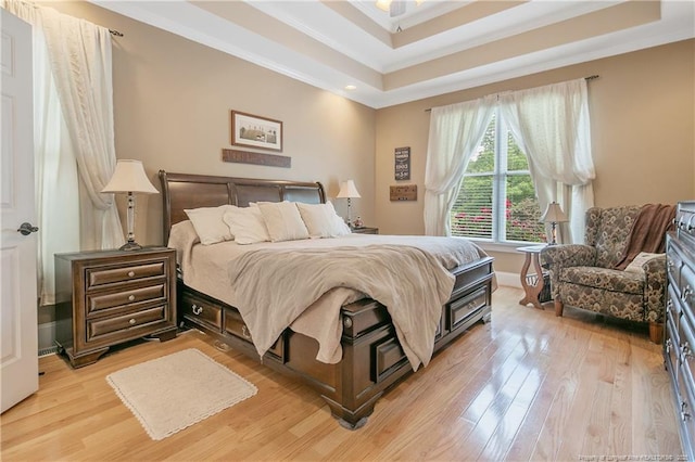bedroom with light wood-type flooring, ornamental molding, a raised ceiling, and baseboards