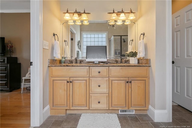 bathroom featuring a stall shower, baseboards, double vanity, and ornamental molding