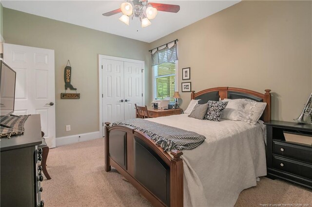 bedroom with light colored carpet, a closet, ceiling fan, and baseboards