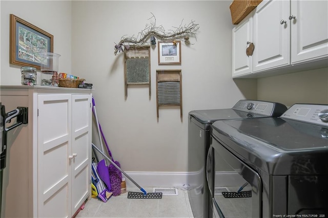 laundry area with independent washer and dryer, cabinet space, baseboards, and tile patterned floors