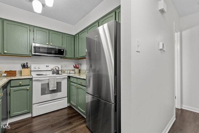 kitchen featuring stainless steel appliances, green cabinetry, dark wood-type flooring, a textured ceiling, and baseboards