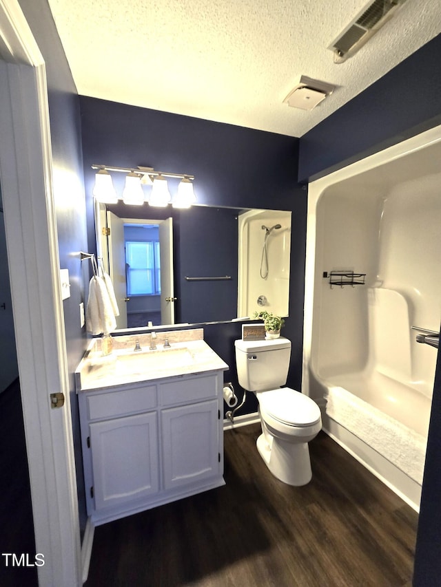 bathroom with a shower, wood finished floors, toilet, vanity, and a textured ceiling