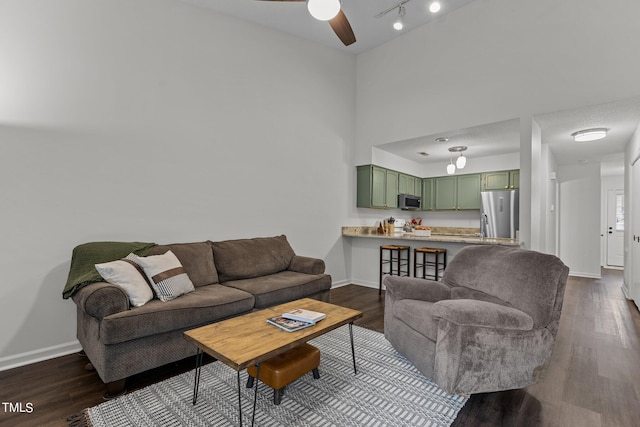 living area featuring baseboards, ceiling fan, and dark wood-style floors