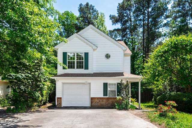 traditional-style home featuring a garage, brick siding, asphalt driveway, and fence