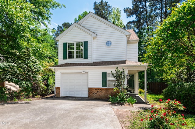 traditional-style house featuring brick siding, a garage, driveway, and fence