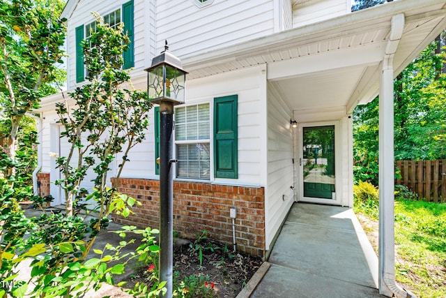 doorway to property featuring brick siding and fence
