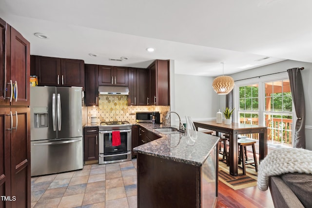 kitchen featuring stainless steel appliances, a sink, under cabinet range hood, a peninsula, and tasteful backsplash