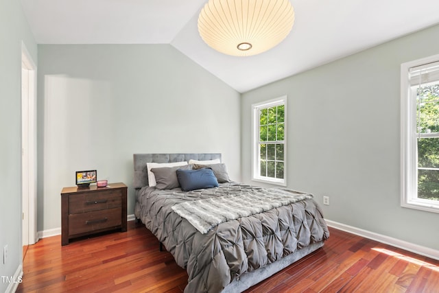 bedroom with vaulted ceiling, multiple windows, and wood finished floors