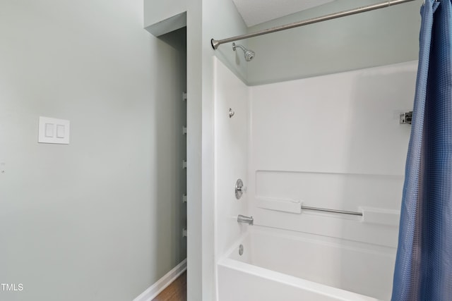 full bath featuring shower / tub combo, baseboards, and wood finished floors