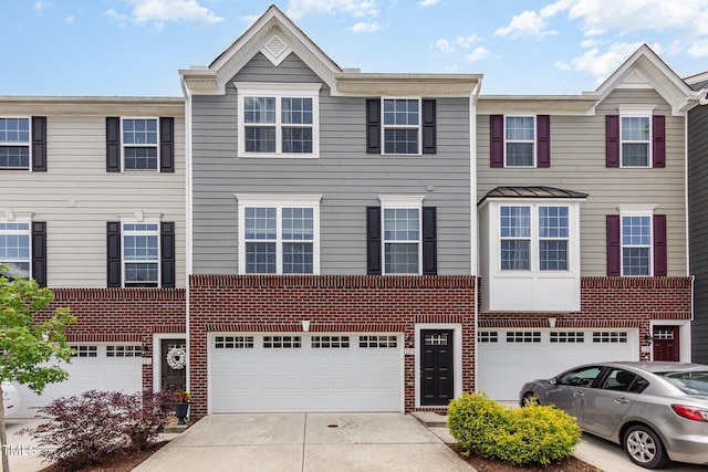 townhome / multi-family property with driveway, brick siding, and an attached garage