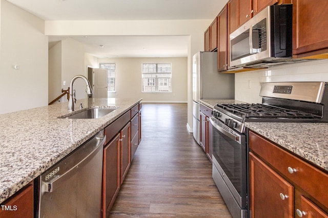 kitchen with stainless steel appliances, a sink, dark wood-style floors, backsplash, and light stone counters