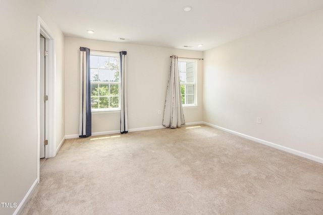 unfurnished room with healthy amount of natural light, light carpet, baseboards, and recessed lighting