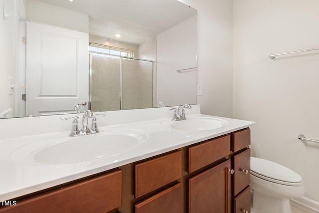 bathroom featuring a stall shower, double vanity, and toilet