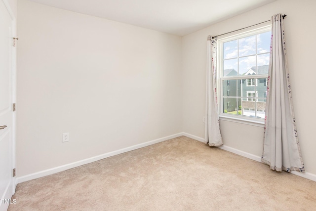 empty room featuring light colored carpet and baseboards