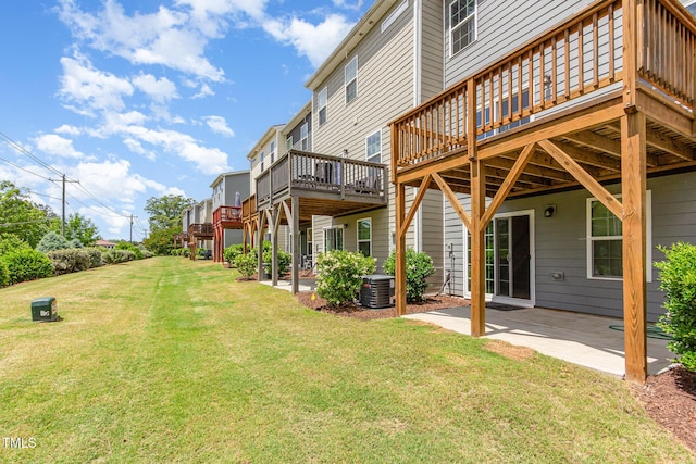 view of grassy yard featuring central AC unit, a patio, and a deck
