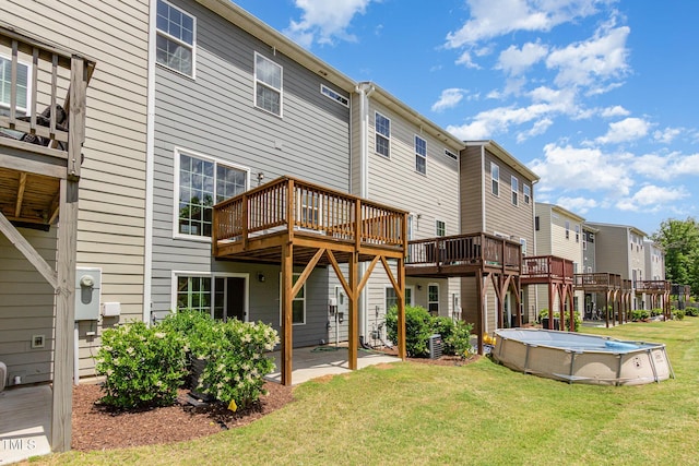 back of property featuring a residential view, a yard, a wooden deck, and an outdoor pool