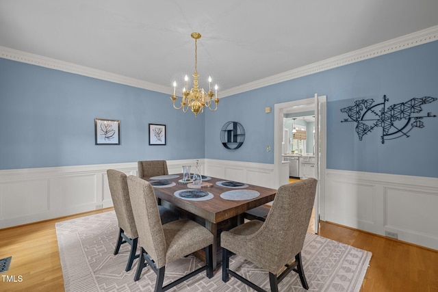 18 Acornridge Ct, Durham, NC 27707 - dining room with a chandelier, light wood-style flooring, wainscoting, crown molding, and a decorative wall
