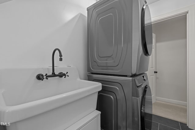 18 Acornridge Ct, Durham, NC 27707 - laundry room featuring stacked washer / drying machine, dark tile patterned floors, and baseboards
