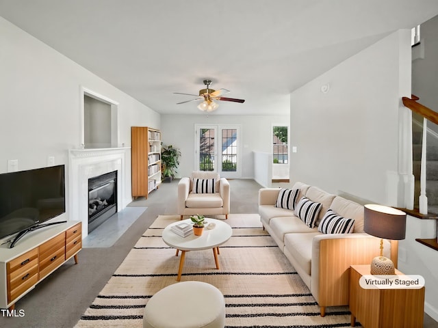 carpeted living area with ceiling fan, a fireplace with flush hearth, and stairs