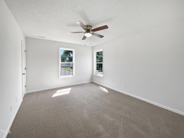 carpeted spare room featuring ceiling fan, a textured ceiling, and baseboards