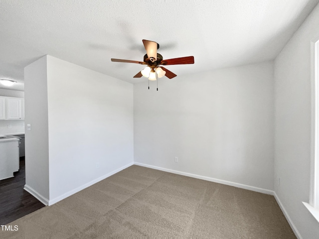 empty room featuring a ceiling fan, dark colored carpet, and baseboards