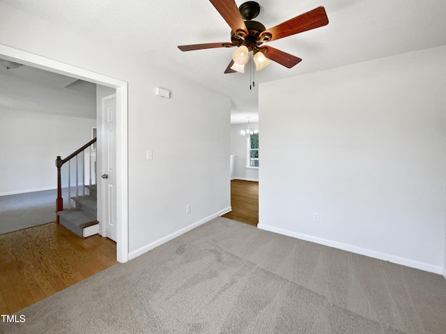 empty room with a chandelier, stairs, ceiling fan, and carpet