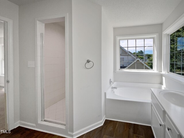 3708 Mackinac Island Ln, Raleigh, NC 27610 - bathroom with wood finished floors, a stall shower, a garden tub, vanity, and baseboards