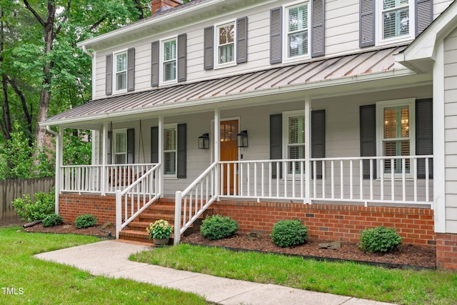 view of front of home with a standing seam roof, covered porch, fence, and metal roof