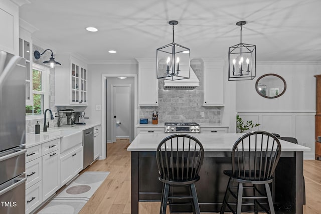 kitchen with appliances with stainless steel finishes, a sink, a chandelier, white cabinets, and light countertops