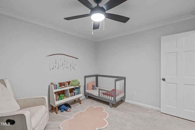 carpeted bedroom featuring a nursery area, ornamental molding, baseboards, and a ceiling fan