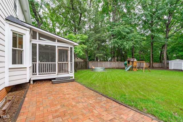 view of yard with a storage shed, a patio area, a sunroom, a playground, and an outbuilding