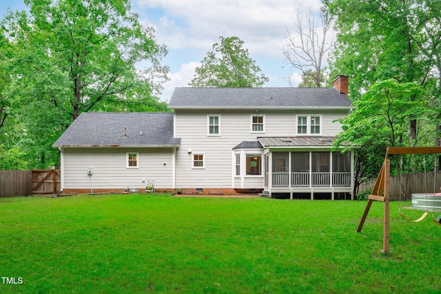 rear view of property featuring a sunroom, a chimney, crawl space, a shingled roof, and a playground