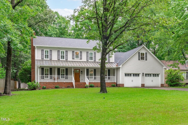 colonial home featuring a standing seam roof, covered porch, a chimney, asphalt driveway, and metal roof