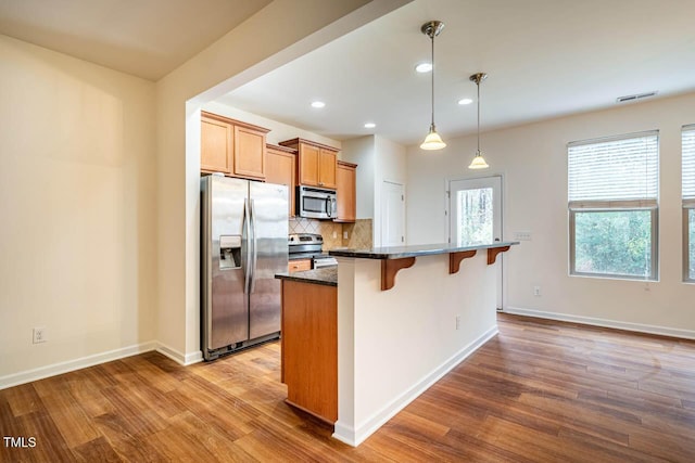 3623 Landshire View Ln, Raleigh, NC 27616 - kitchen featuring stainless steel appliances, a breakfast bar area, wood finished floors, backsplash, and a kitchen island