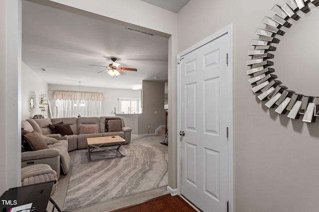 living area featuring a ceiling fan, baseboards, and dark wood-style floors