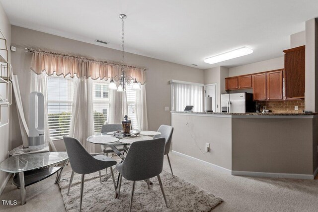 dining room featuring a chandelier, baseboards, and light colored carpet