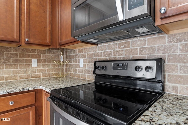 kitchen with appliances with stainless steel finishes, brown cabinetry, decorative backsplash, and light stone counters