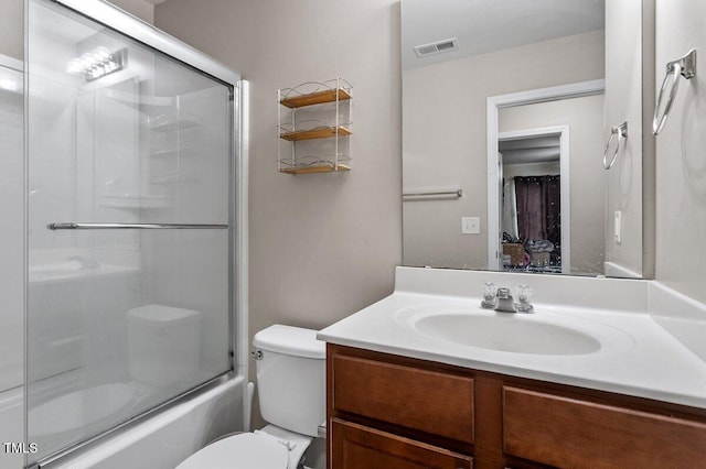 full bathroom featuring vanity, toilet, and shower / bath combination with glass door
