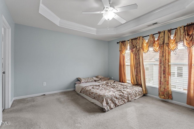 carpeted bedroom featuring a tray ceiling, crown molding, baseboards, and a ceiling fan