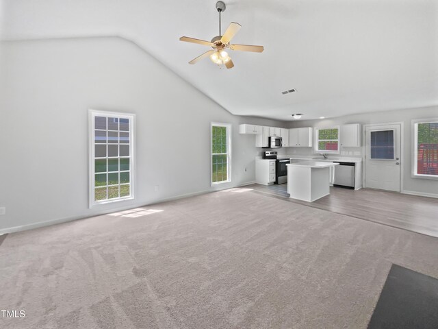 5612 Tealbrook Dr, Raleigh, NC 27610 - unfurnished living room featuring light carpet, baseboards, ceiling fan, and high vaulted ceiling