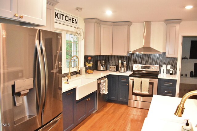 3141 Wagoner Ln Unit 09, Graham, NC 27253 - kitchen featuring appliances with stainless steel finishes, wall chimney exhaust hood, light countertops, light wood-type flooring, and decorative backsplash